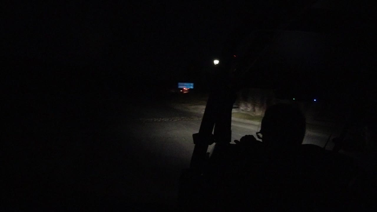 Dark vehicle view of a road lit by headlights at night.