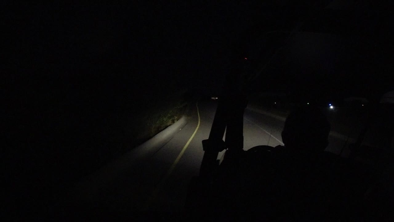 Dark vehicle interior with headlights on a road ahead.