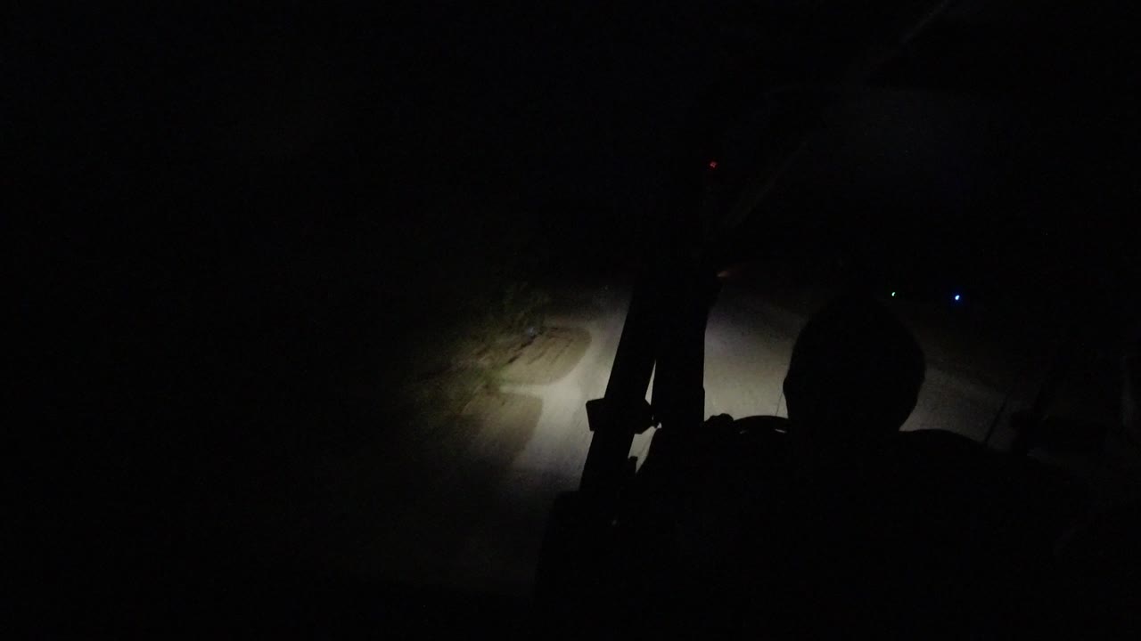 Vehicle lights reveal the road edge in darkness