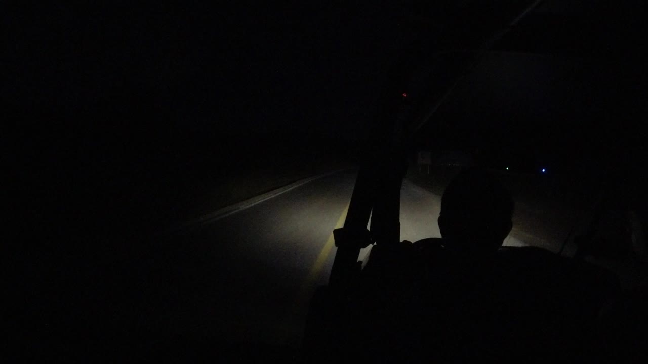 One second in, the Los Cabos night ride remains mostly black, with the occupant silhouette centered lower in frame and headlights falling across the pavement.