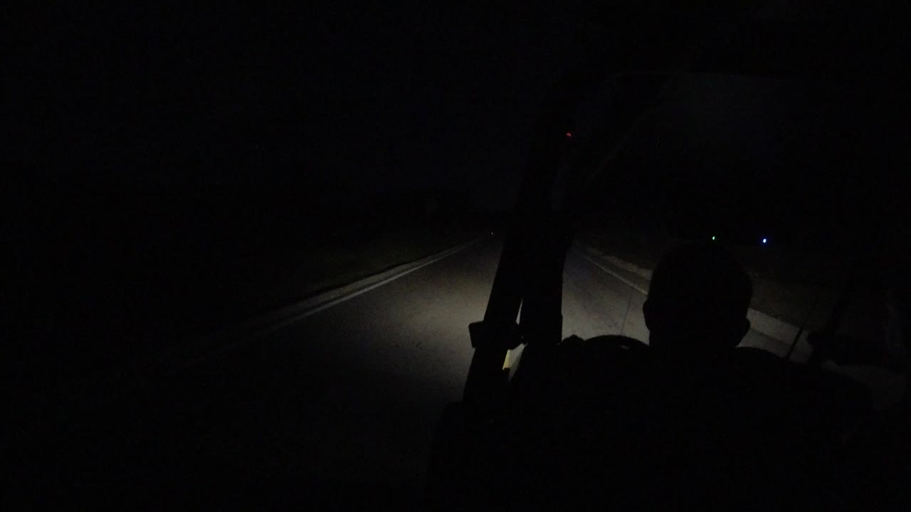 Dark road seen past Wrangler interior silhouettes and headlights.