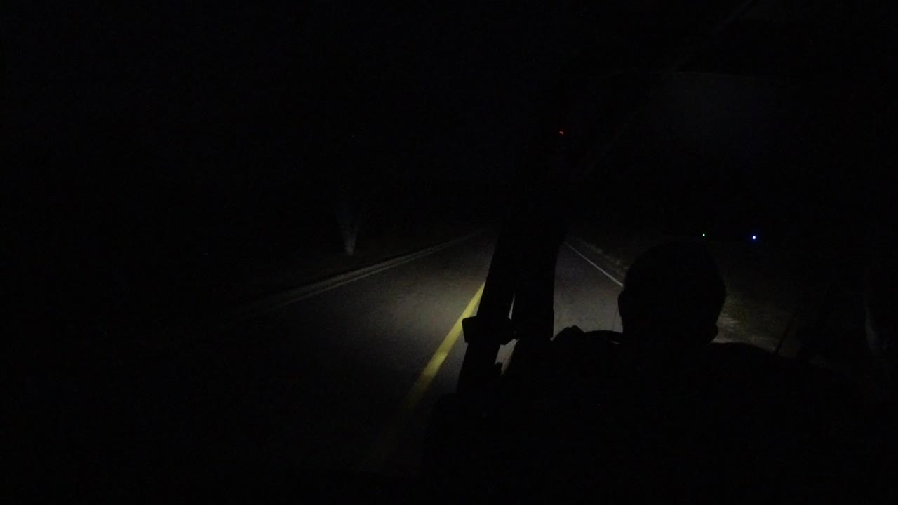 Dark road ahead lit by vehicle headlights