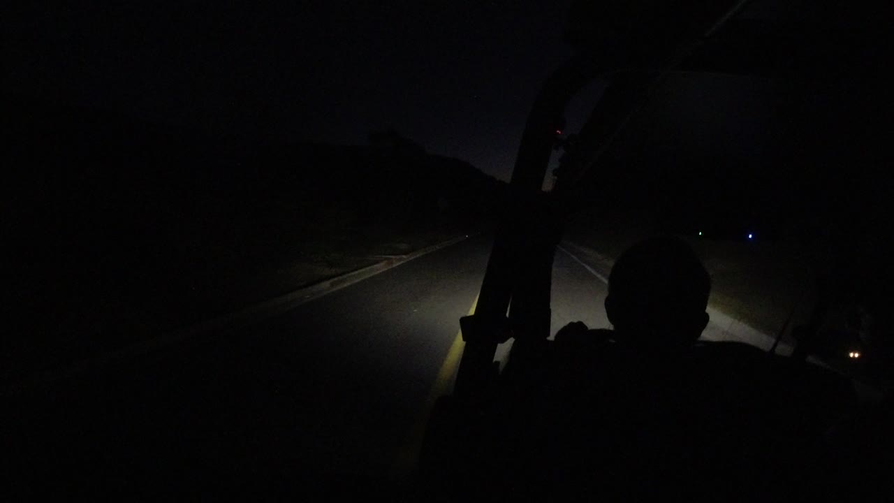 A second dark Los Cabos road view shows the driver's head and shoulders in silhouette, with the headlight beam spreading across the lane ahead.