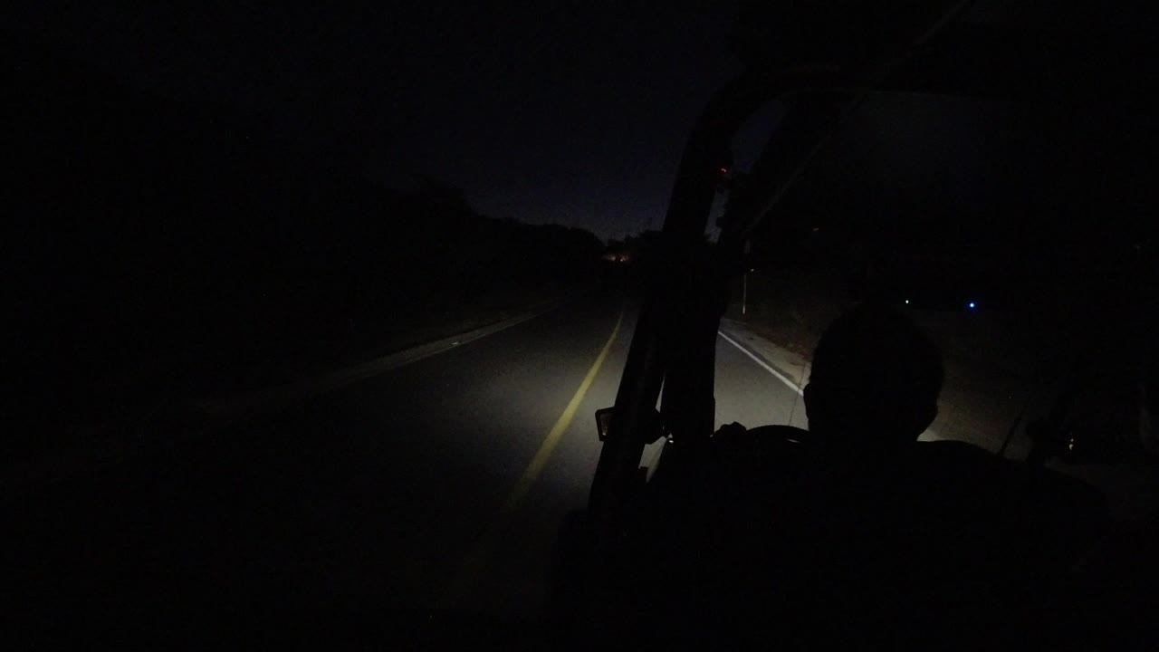 Dark car interior facing a headlit road at night.