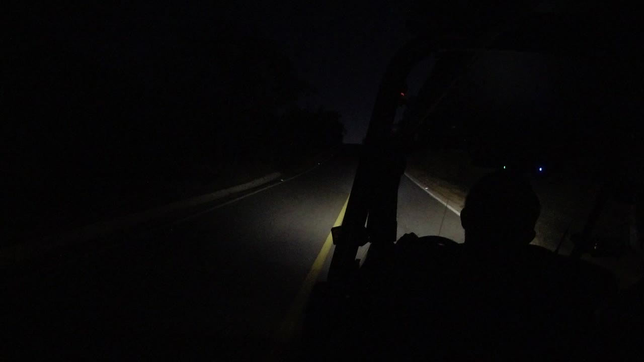 Dark vehicle interior with driver silhouette and headlights on a road