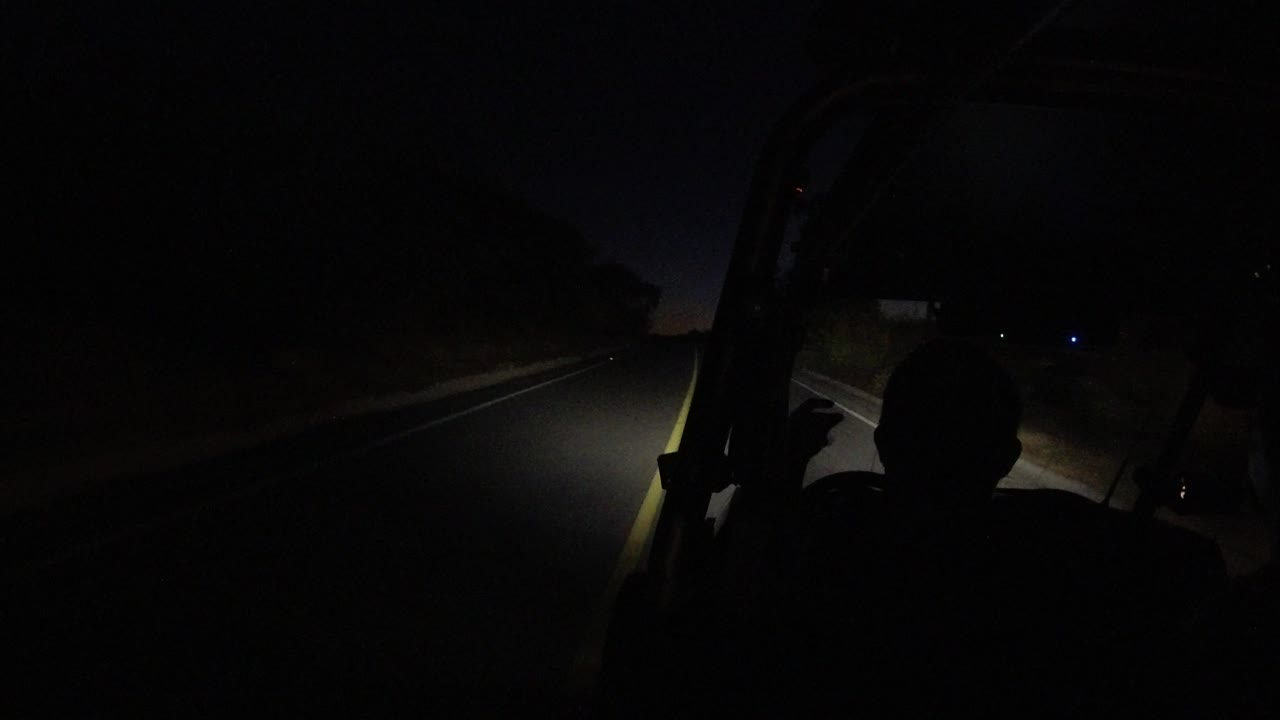 Dark RZR interior view with headlights pointed along the road.