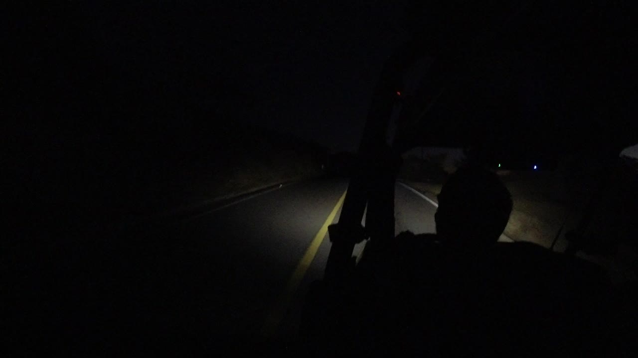 Opening frame of a dark road in Los Cabos, Mexico, seen through a vehicle windshield with a yellow lane line and no clearly visible people.