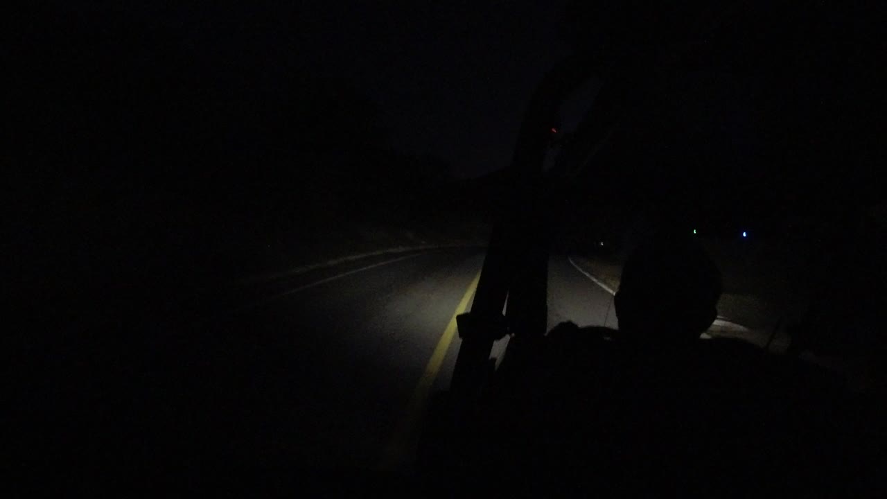Dark road ahead seen from inside an open vehicle at night.