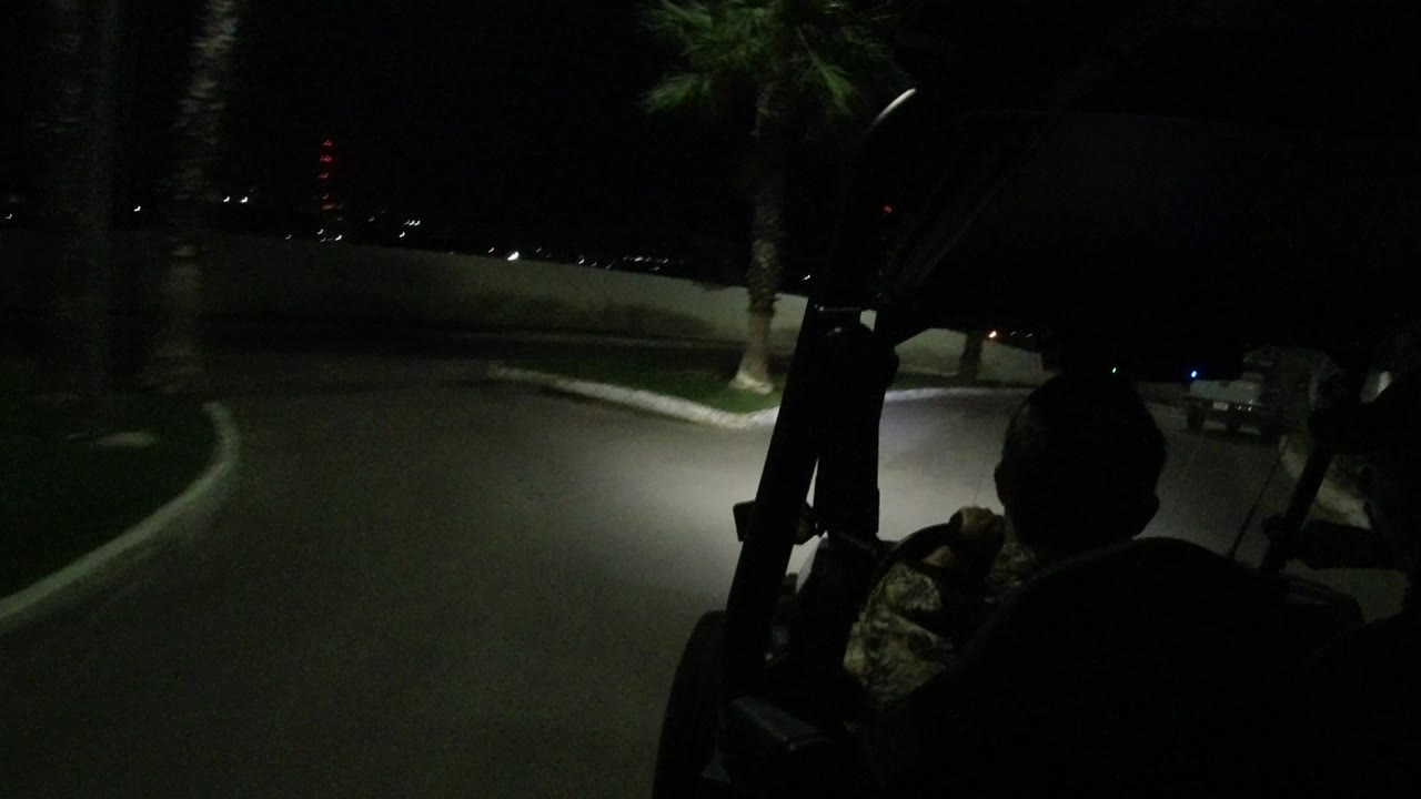 At the start of the Los Cabos clip, a dark road curves past a low wall and palm tree while silhouetted Jeep occupants sit in the foreground.