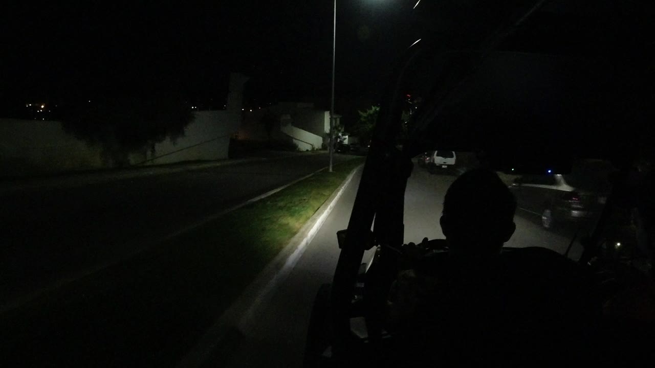 Dark road seen from a jeep with curb and streetlight