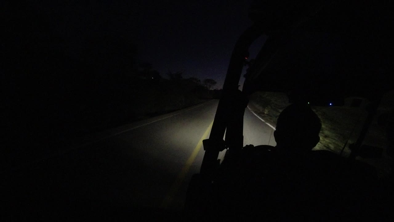 Vehicle windshield view of a dark road with a silhouetted head shape.