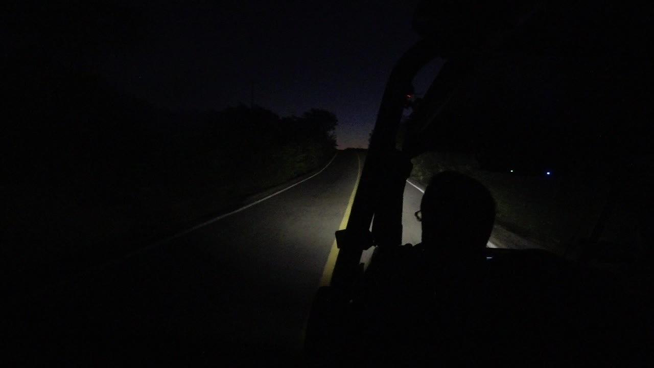 One second in, the Los Cabos road remains mostly black, with the Jeep structure framing the right side and headlights catching the lane line and roadside vegetation.
