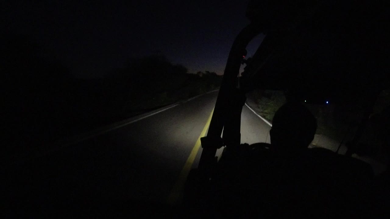 Dark road seen from inside a Jeep with a silhouetted passenger.