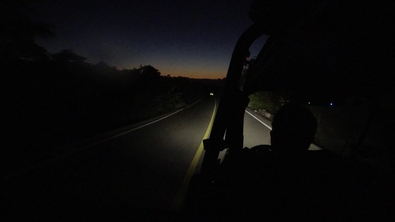 Dark road ahead lit by headlights from inside a vehicle.