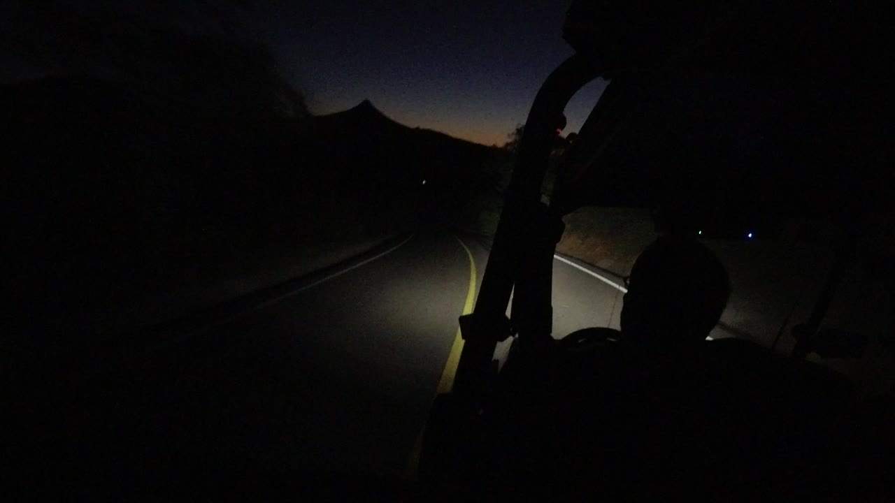 Dune buggy rider silhouette on a dark paved road at night.