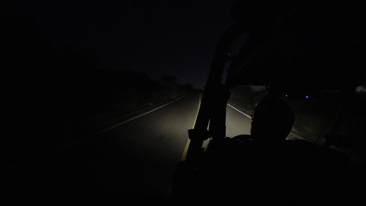 Dark road ahead through jeep headlights with driver silhouette