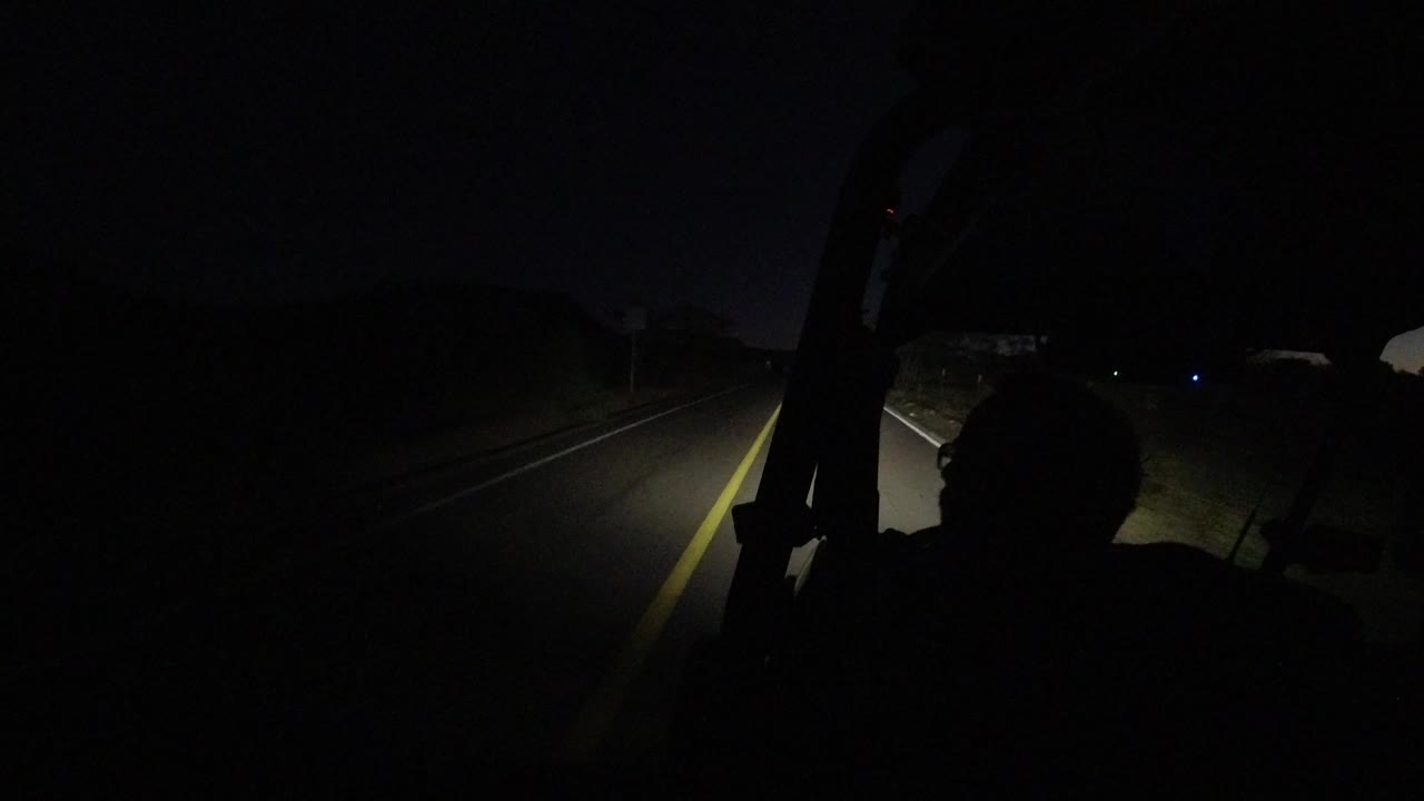 Dark vehicle interior looking onto a headlit road at night.