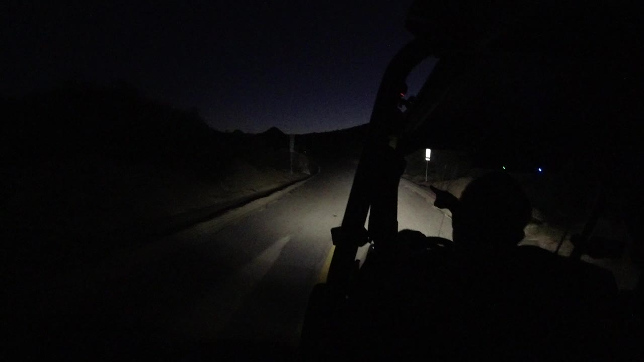 Dark road ahead from a Jeep with a silhouetted occupant in front.
