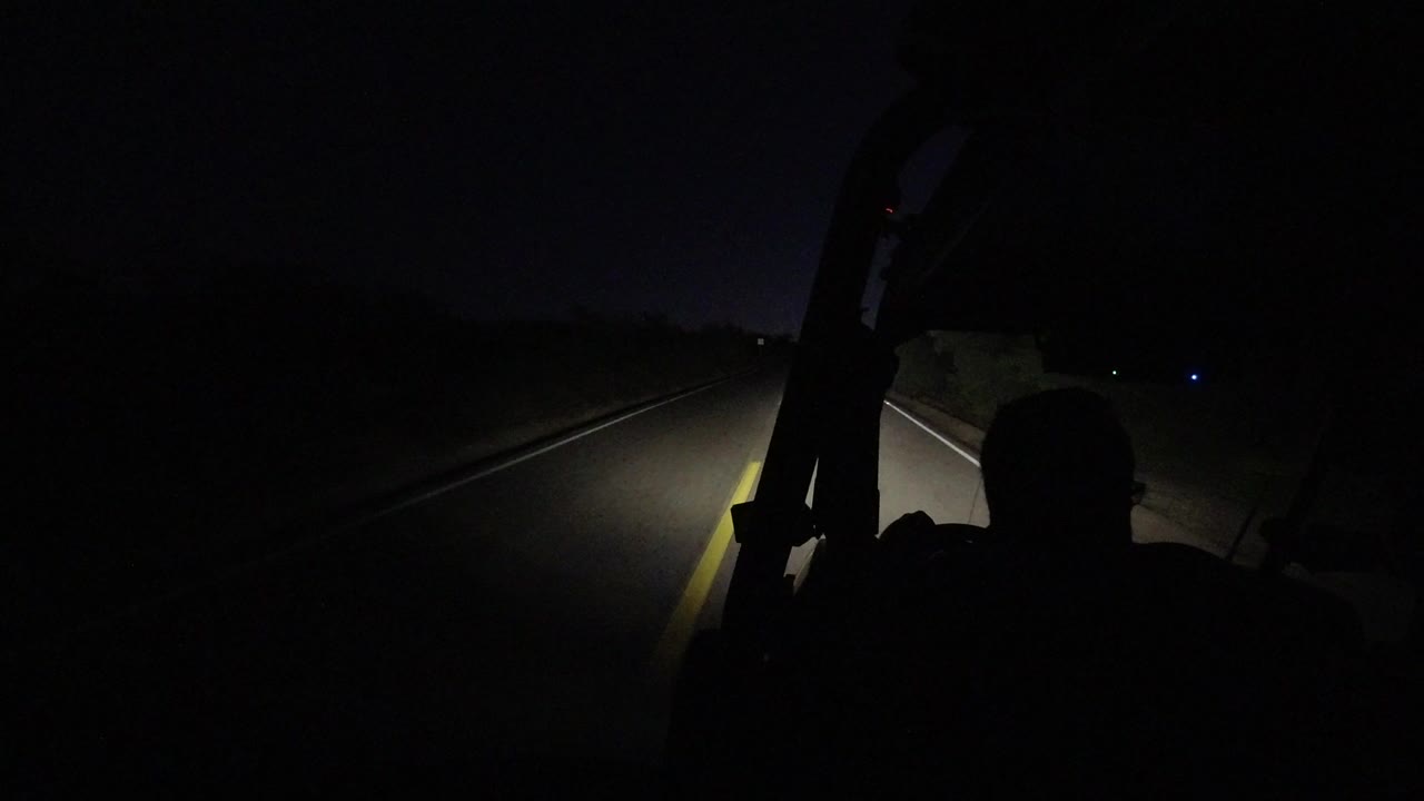 Dark highway seen from behind a silhouetted driver at night