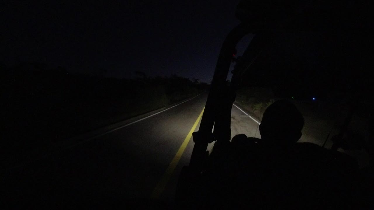 Dark road seen through a car windshield at night.