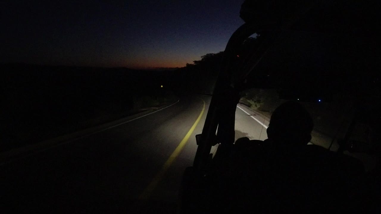 At 0:00 in Los Cabos, Mexico, a dark road curves ahead under headlights while a silhouetted person and vehicle frame fill the lower foreground.