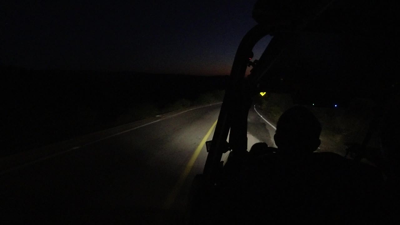 Low-light car interior looking toward a road and roadside reflector.