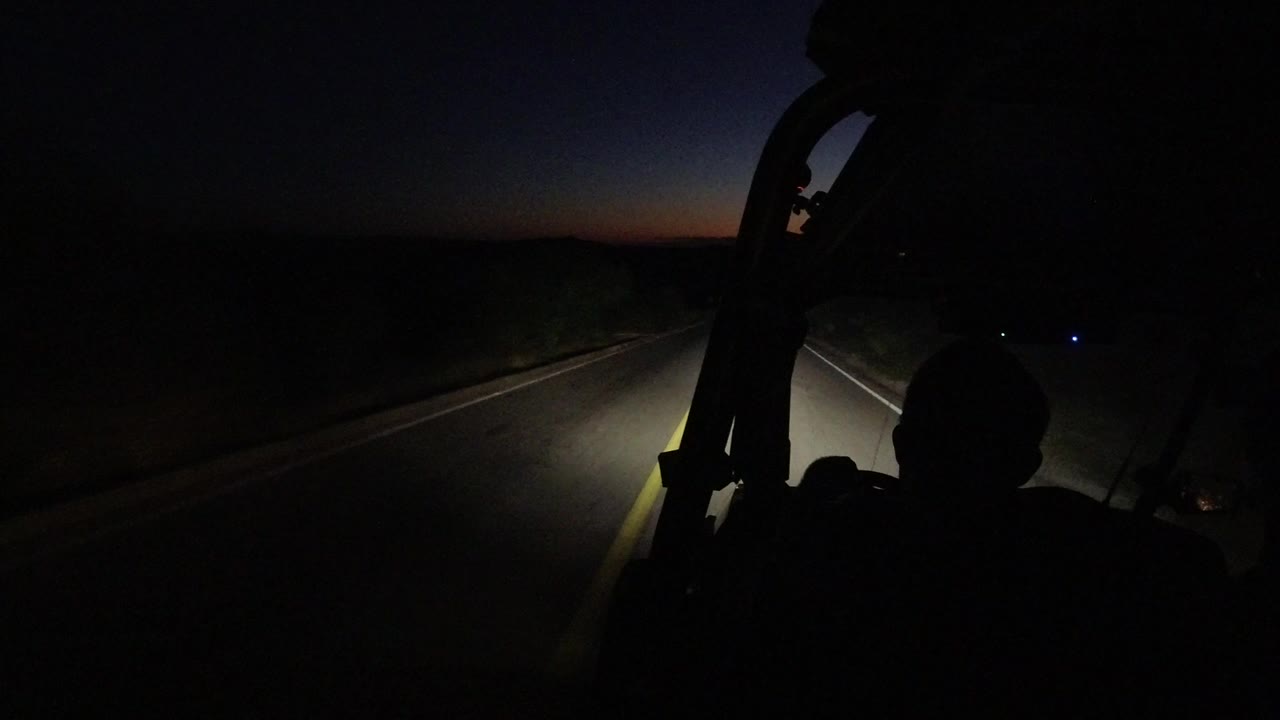 Dark road ahead through a vehicle windshield at dusk