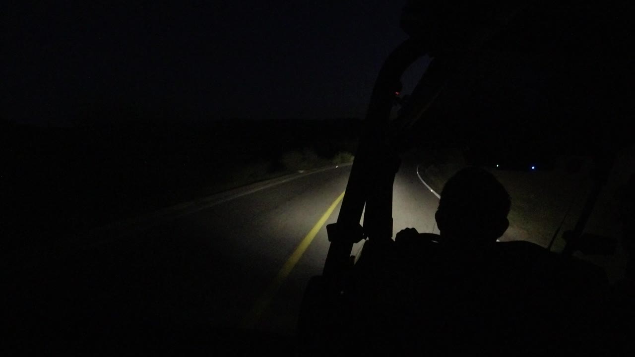 At 0:01 in Los Cabos, Mexico, the road curves through darkness as the driver's silhouette remains at the lower right and the headlights pick out lane markings.