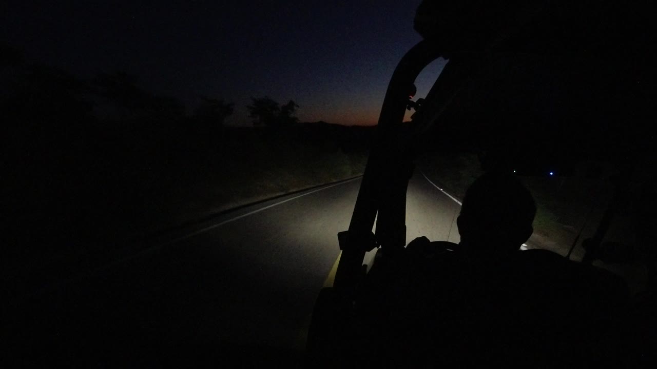Jeep roll bar silhouetted against a dark road