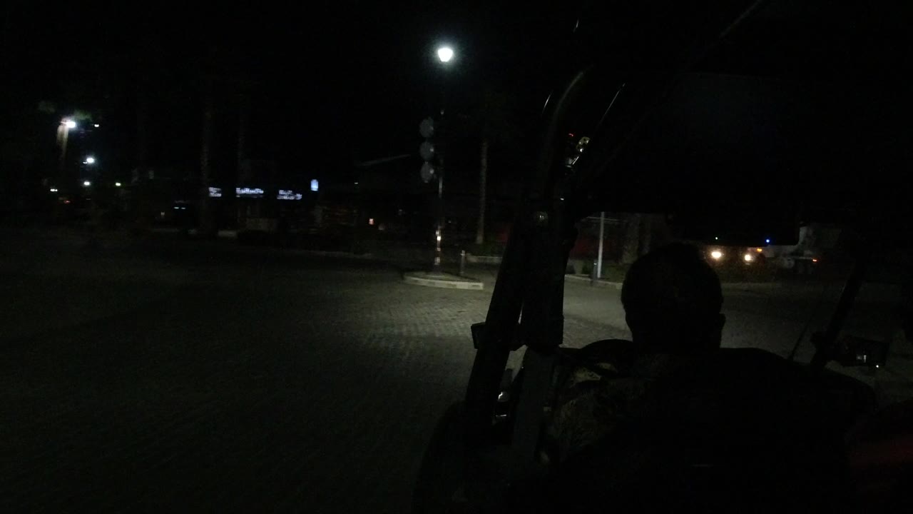 Dark road seen through a vehicle windshield with a driver silhouette.