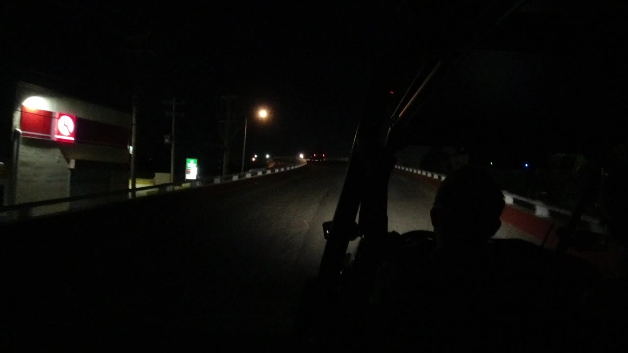 Dark paved road beside an illuminated building and roadside sign