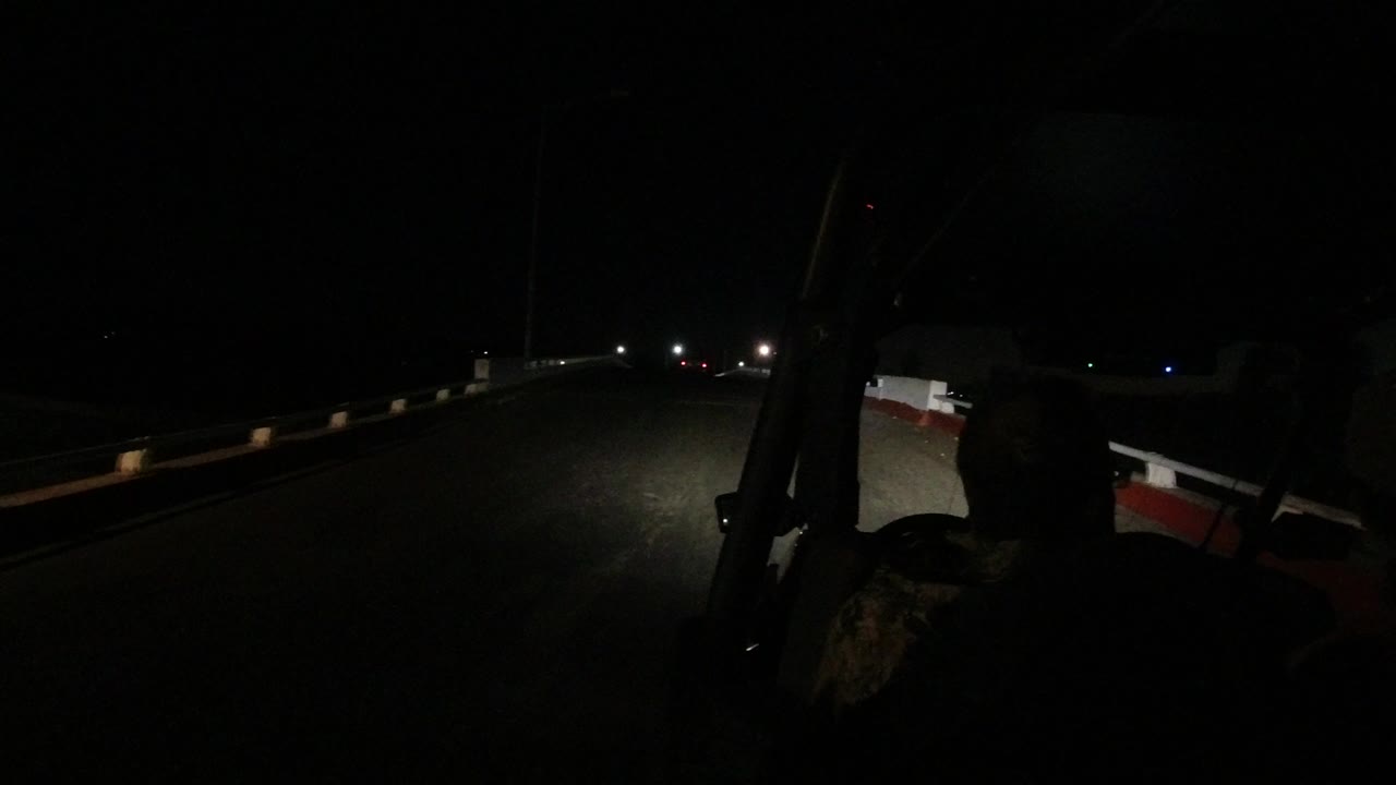 Dark road ahead from inside a vehicle with a driver silhouette.