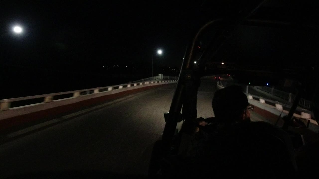 Dark night road with streetlights and a man seen from behind