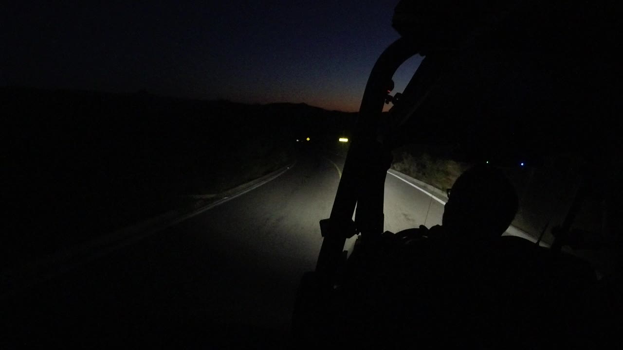 One second in, the Los Cabos road remains mostly black except for a bright headlight patch and the shadowed outline of a person near the lower right.