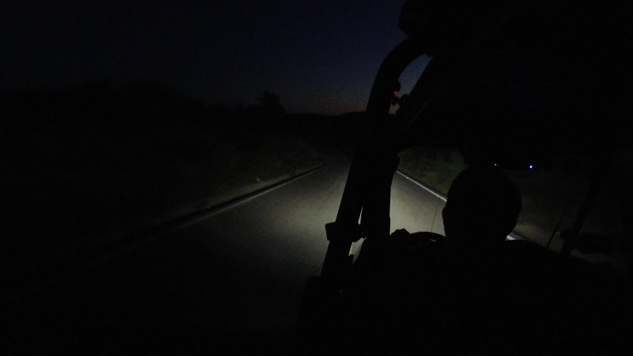Night road and headlight beam with a faint blue light to the side.