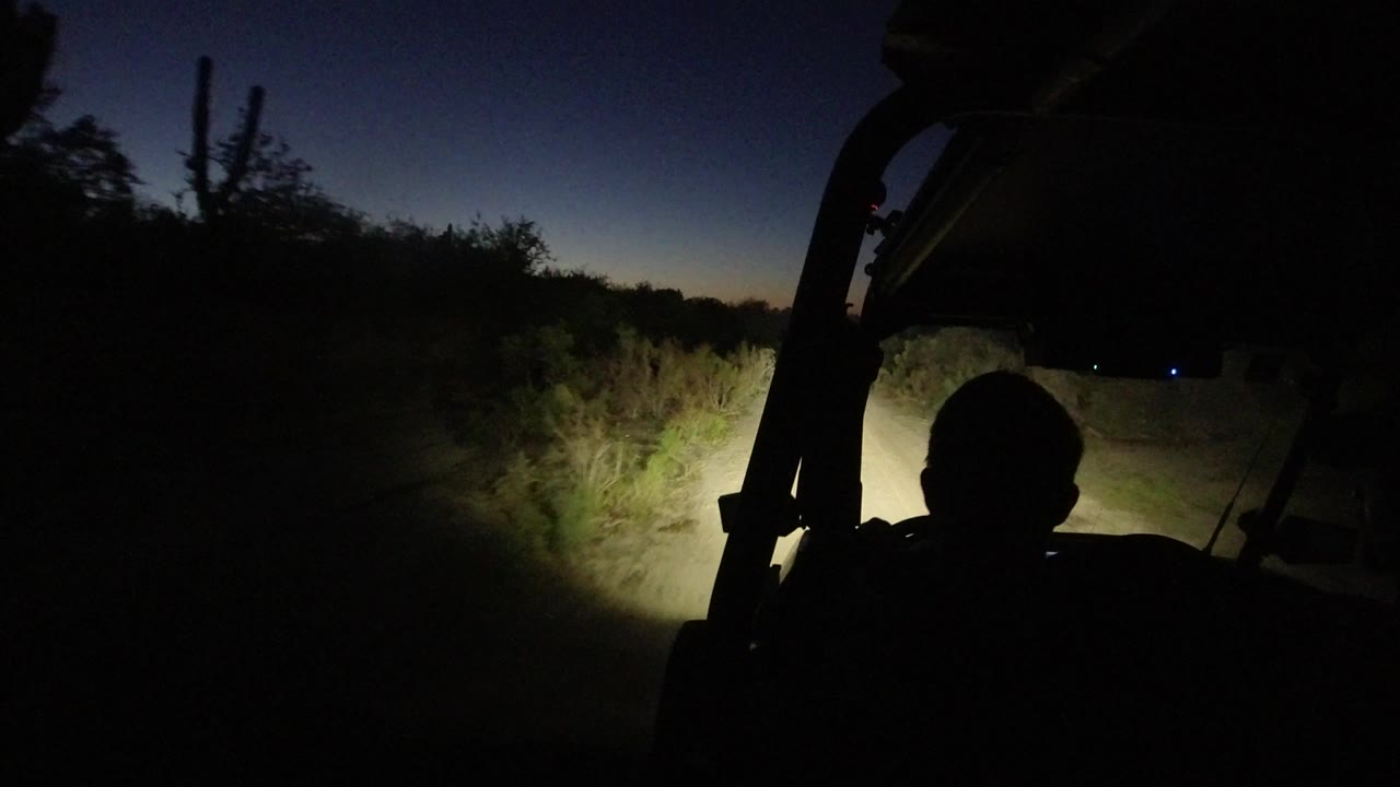 Jeep silhouette against a dark desert road at night.