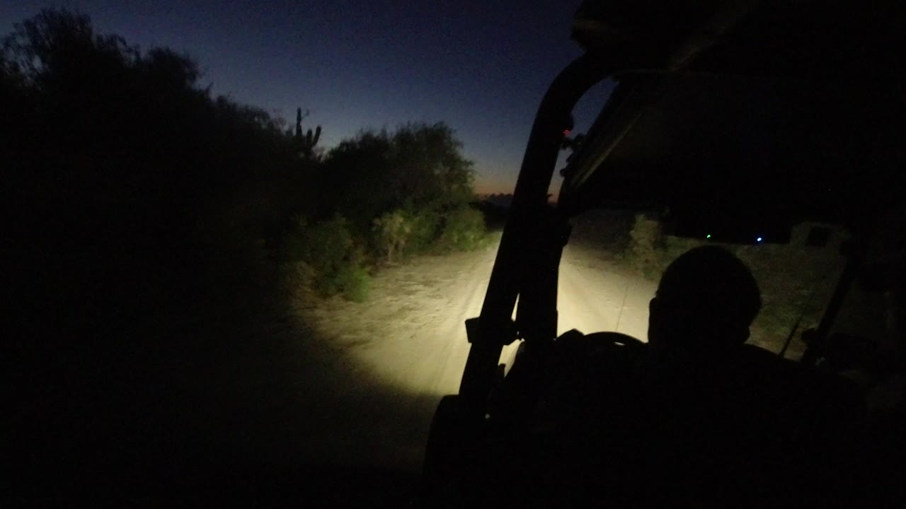 Driver silhouette on a dark road lit by headlights