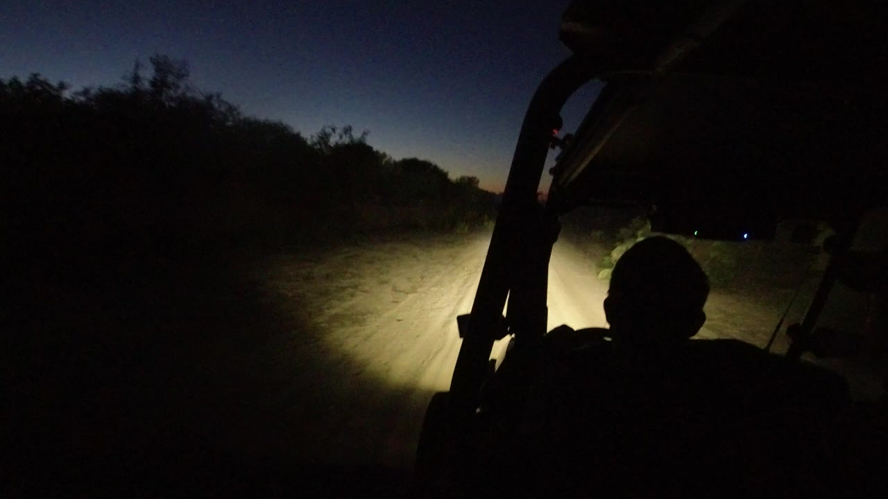Silhouetted driver on a dark dirt road at dawn