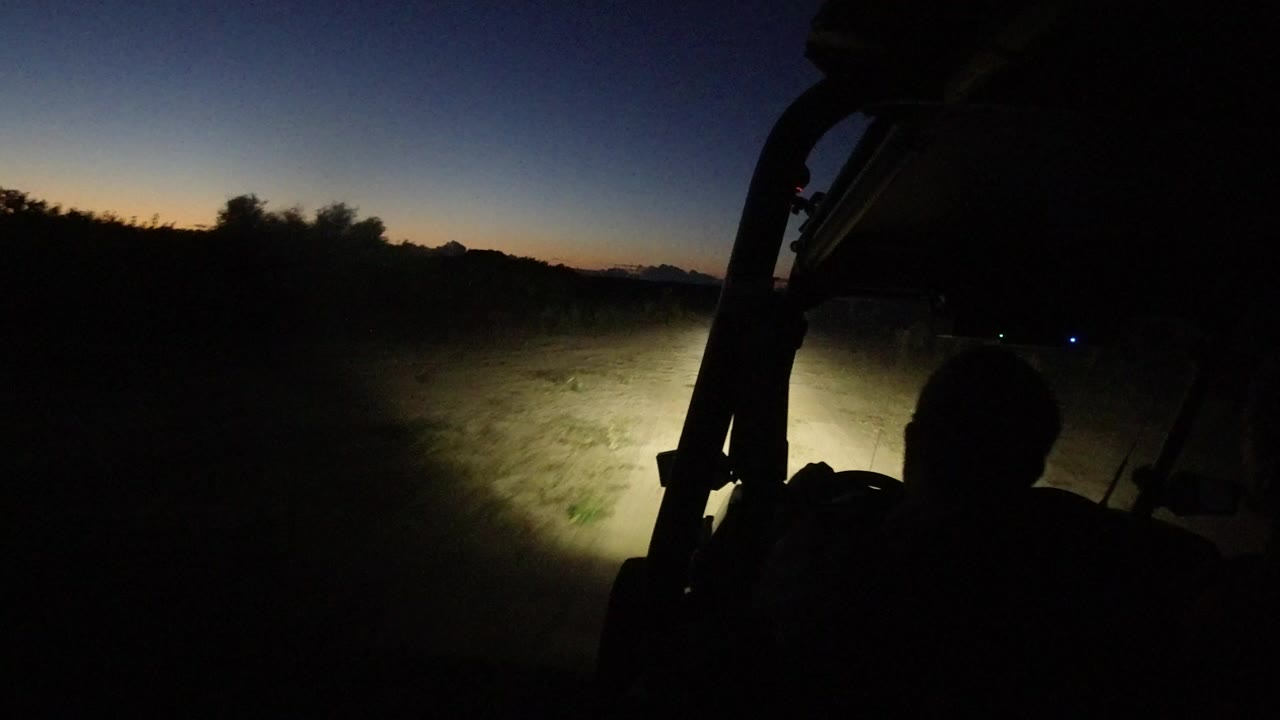 Dark vehicle interior facing a sandy track at dusk.