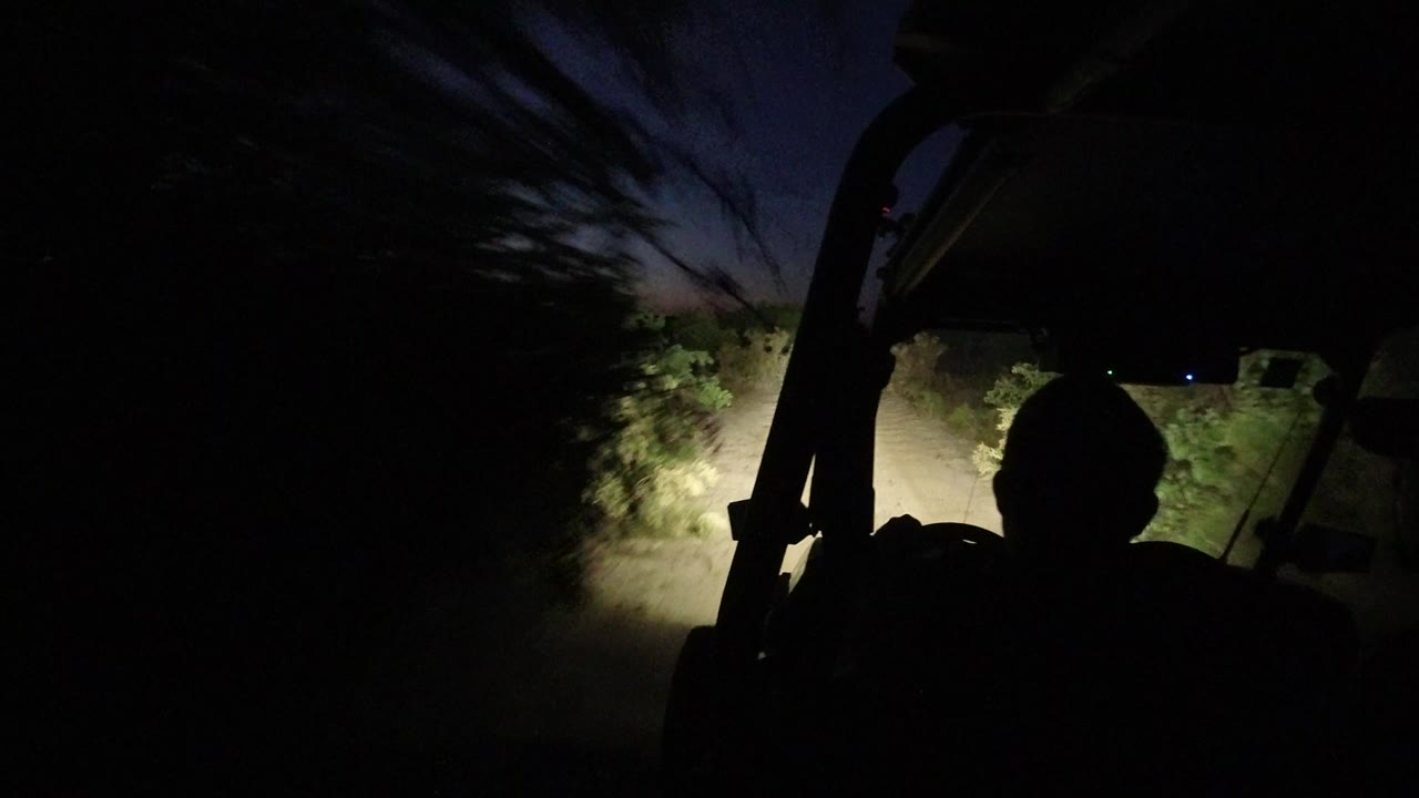 Silhouetted driver on a dark dirt road at dusk