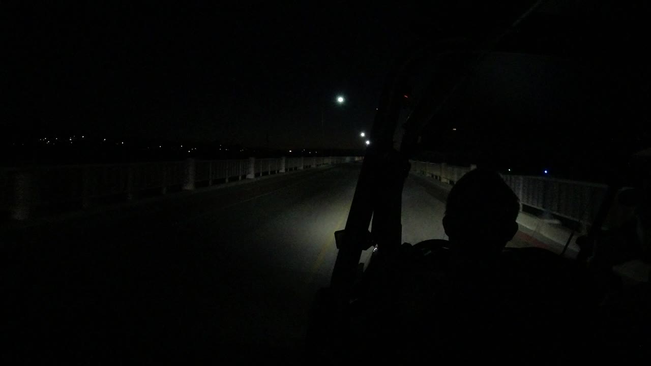 Dark bridge road seen from a vehicle at night.