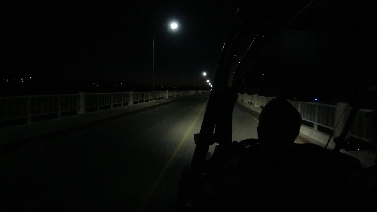 Forward road view at night with guard rails and distant lights.