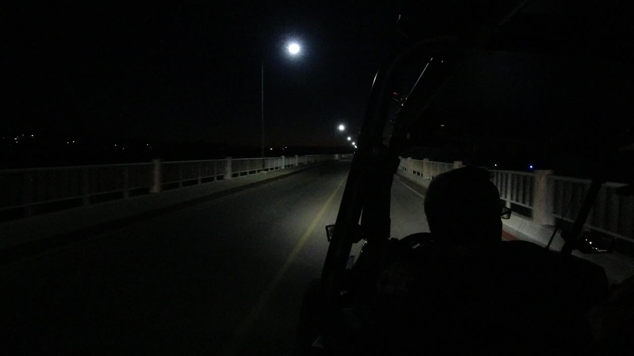 Night bridge road seen from a Jeep with silhouetted occupants.