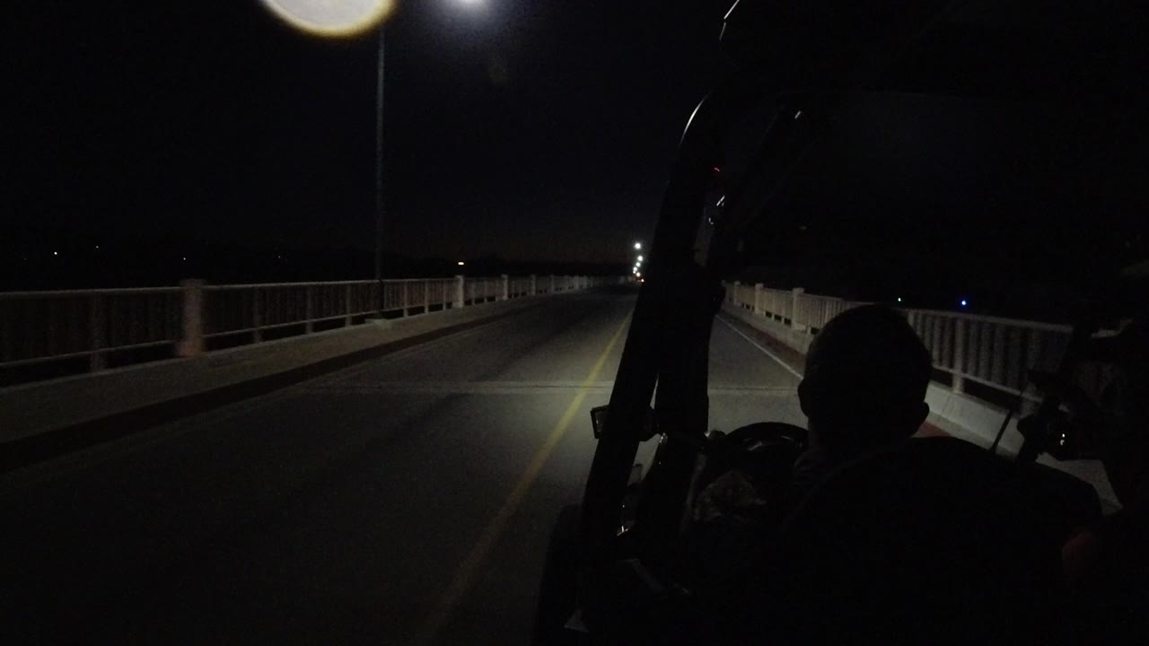 Bridge lane and railings lit by headlights at night.