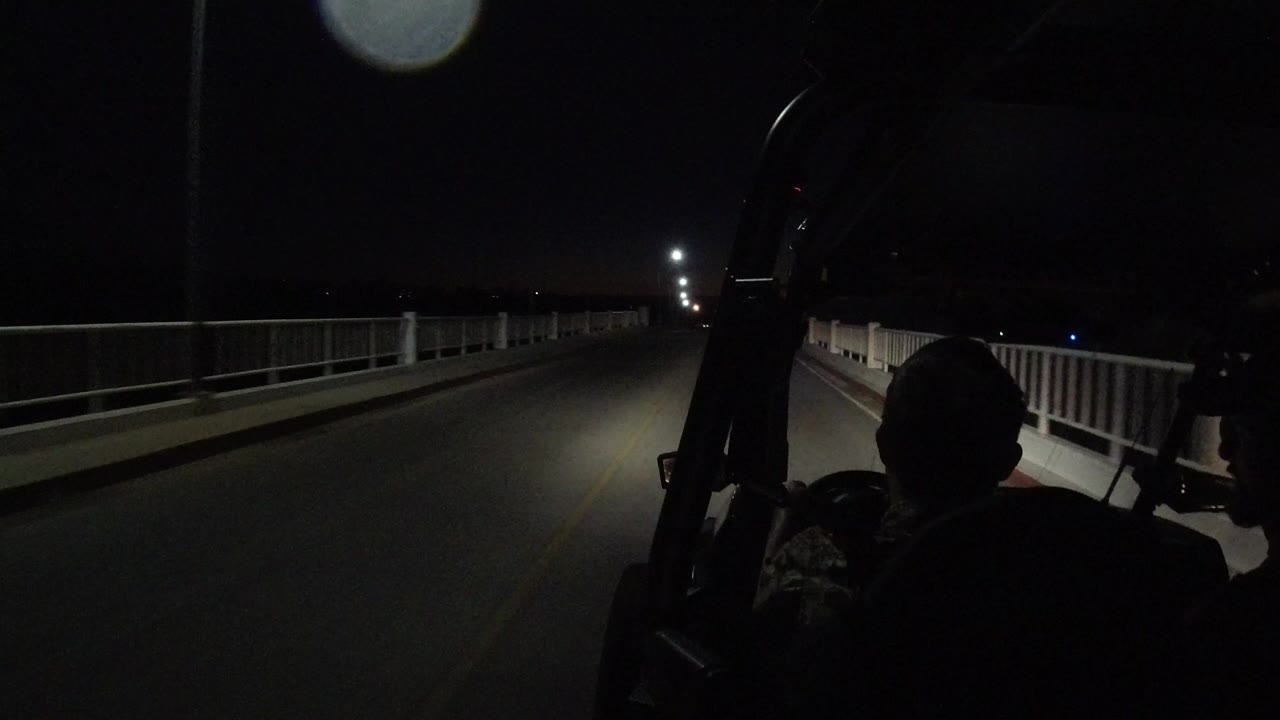 At the start of the Los Cabos night drive, an empty road with white railings and streetlights stretches ahead while silhouetted occupants sit in the foreground.