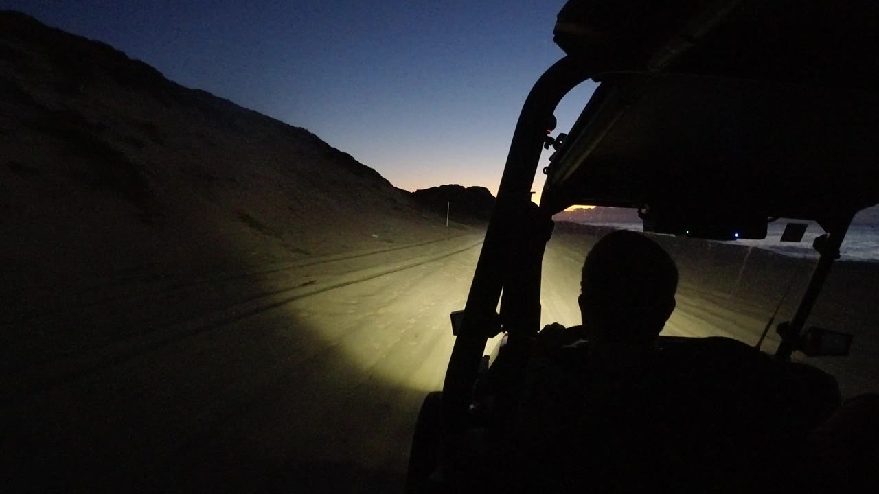 Open vehicle frame and occupant silhouette on a coastal desert road.