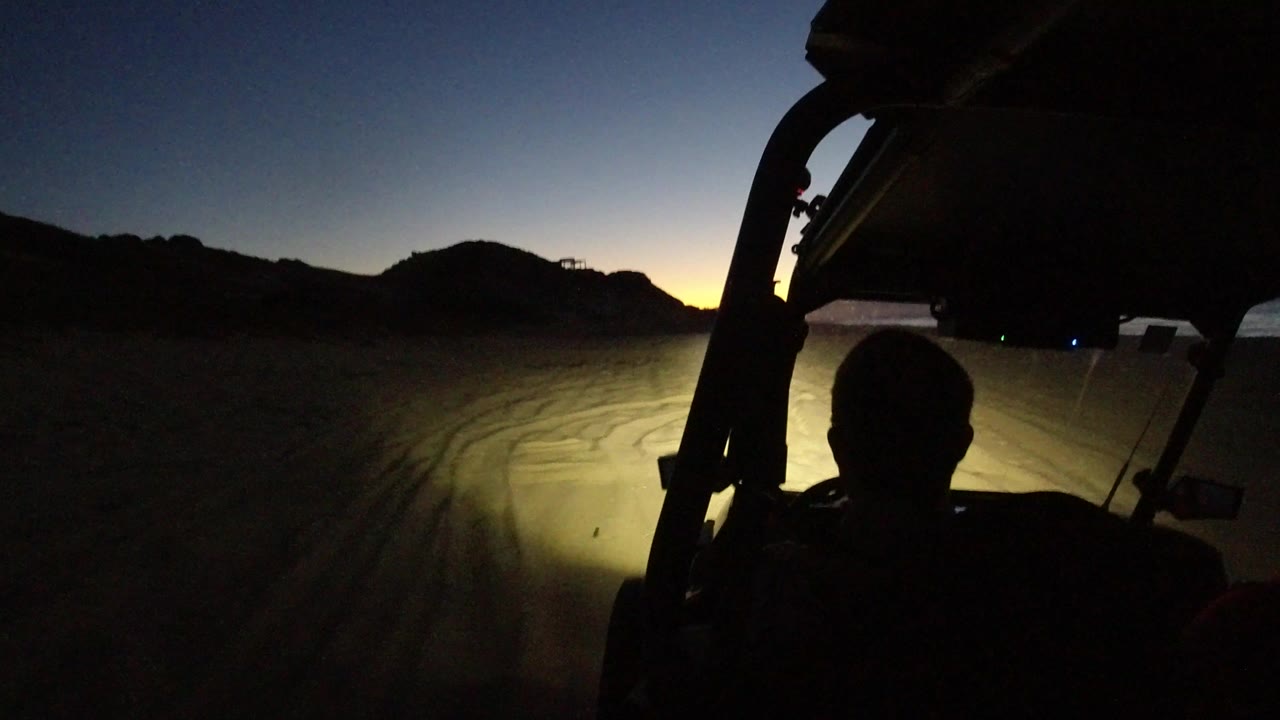 Dune buggy interior silhouette facing sandy terrain at dusk.