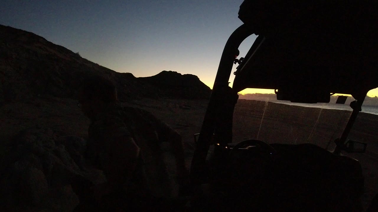 Dark vehicle silhouette with mountains at sunset