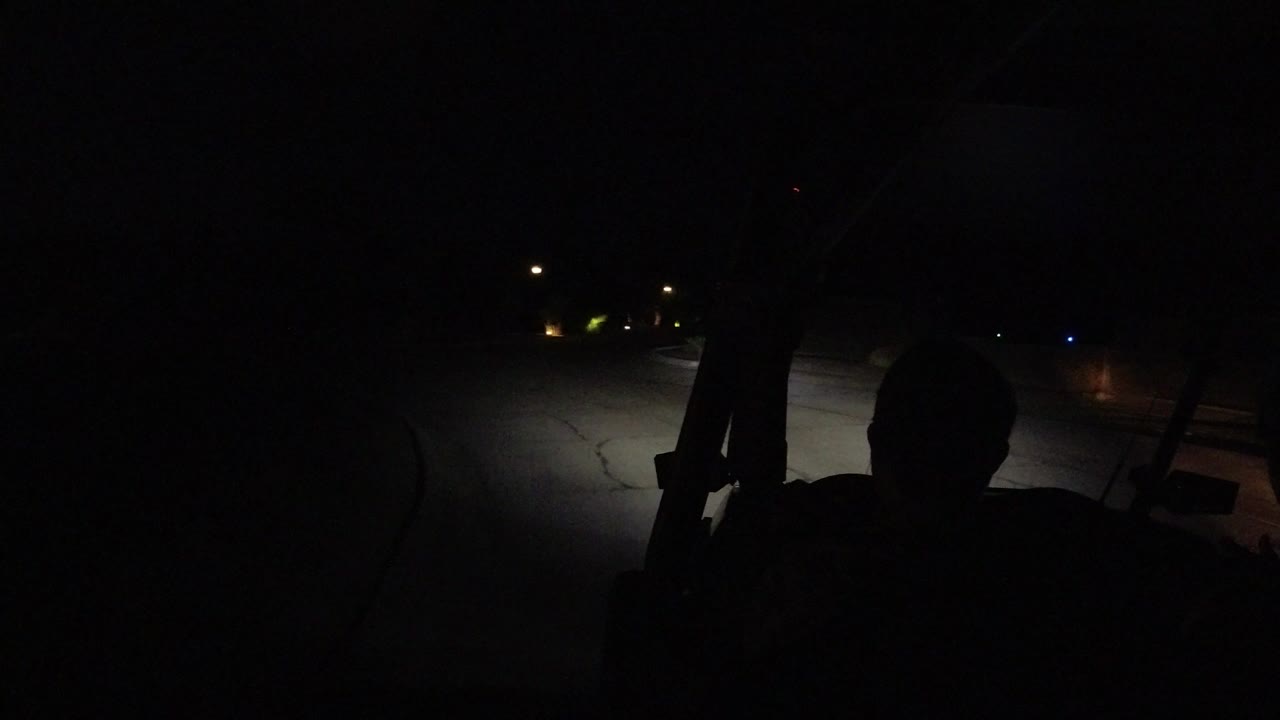 Dark road seen past a silhouetted man in a vehicle