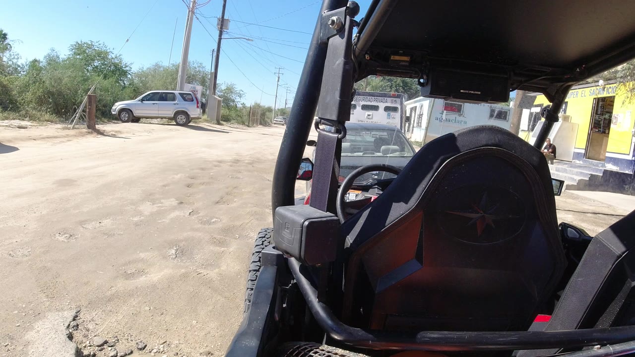 Open vehicle seat beside a dusty road and parked SUV